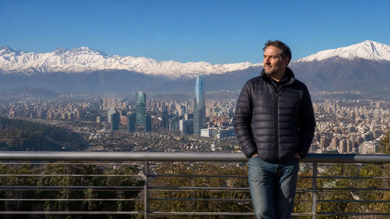 Auswanderer auf einem Aussichtspunkt ueber Santiago mit den schneebedeckten Anden hinter der Skyline.