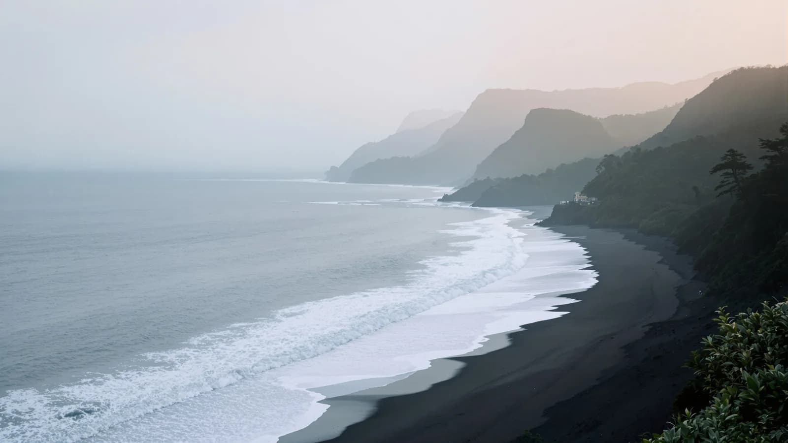 Weite Pazifikbucht am Nachmittag, Regenwald reicht bis ans Wasser, leerer dunkler Sandstrand.