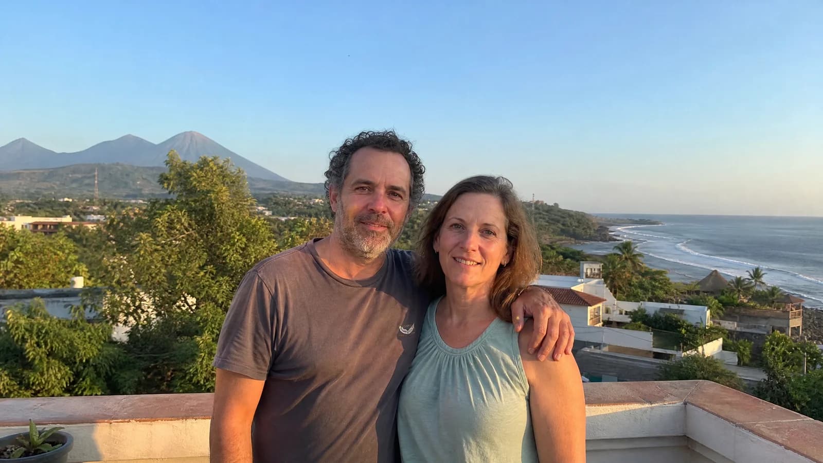Paar auf einer Dachterrasse in El Salvador mit Vulkanen und Pazifik im Hintergrund im warmen Abendlicht.