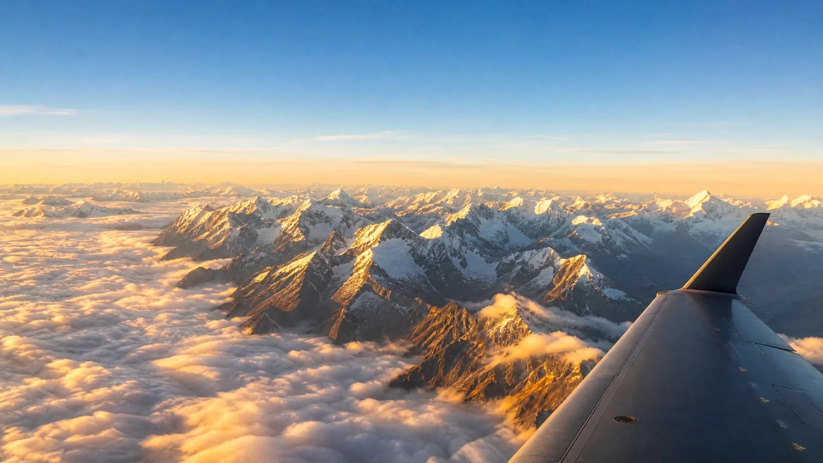 Blick aus einem Flugzeugfenster über die schneebedeckten Anden im goldenen Licht