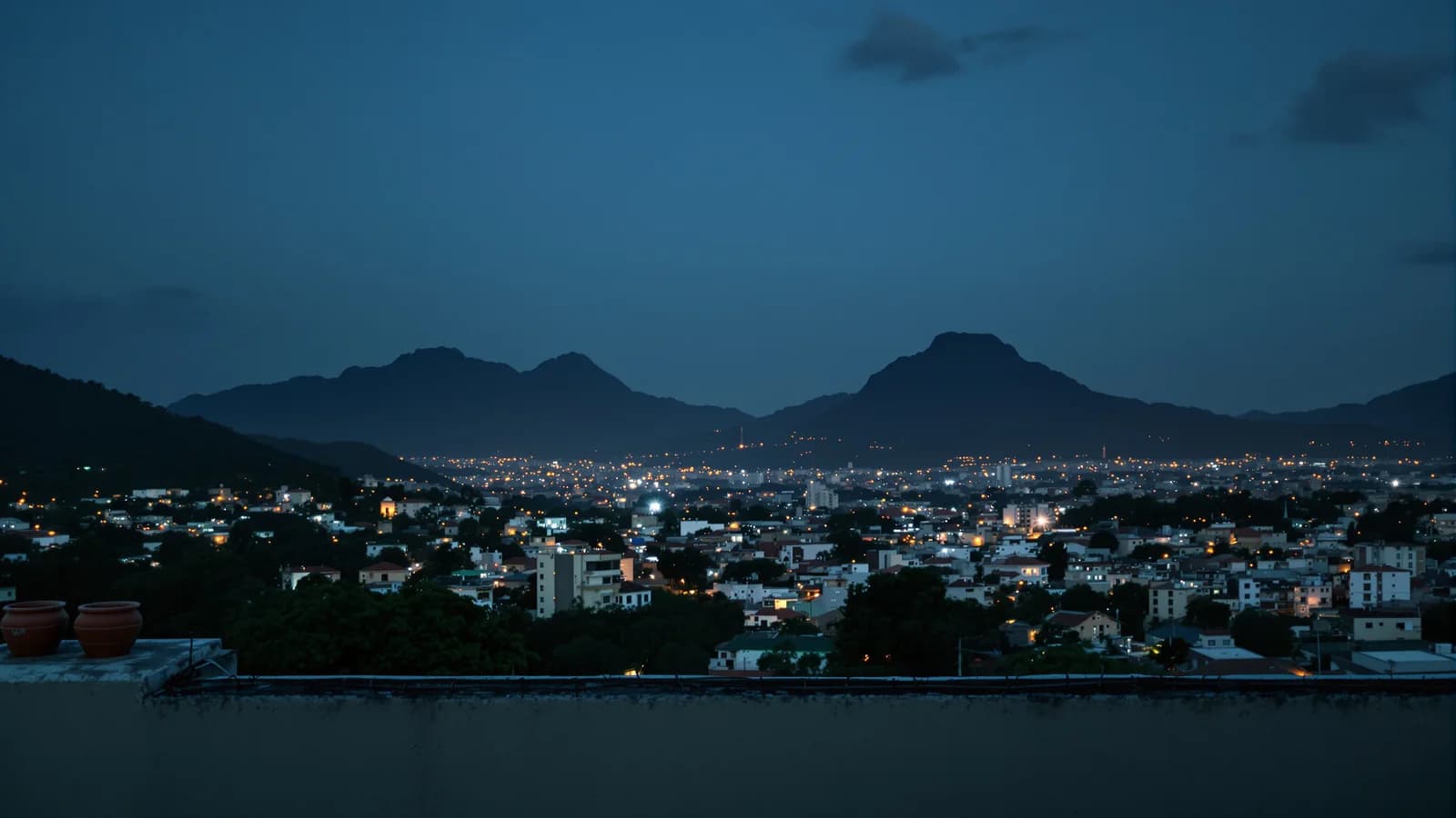 Abendblick über das Lichtermeer einer lateinamerikanischen Großstadt bis zu dunklen Bergen.
