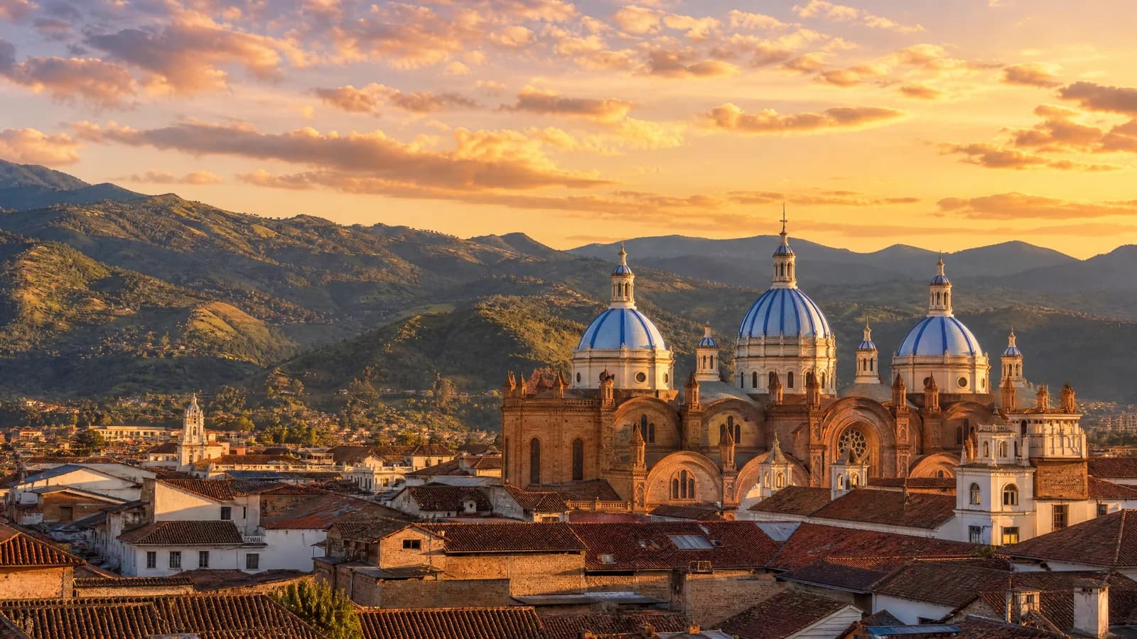 Blaue Kuppeln der Kathedrale von Cuenca, Ecuador, über den Dächern der Altstadt im Abendlicht